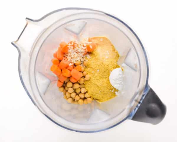 Ingredients like carrots and chickpeas are in the bottom of a blender.