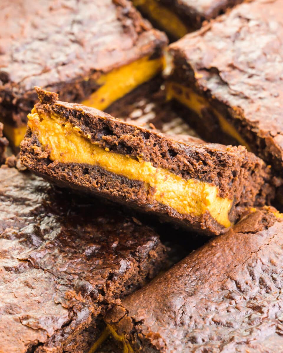 Looking down on a pumpkin brownie with a bite taken out sitting in a pan with more brownie slices.