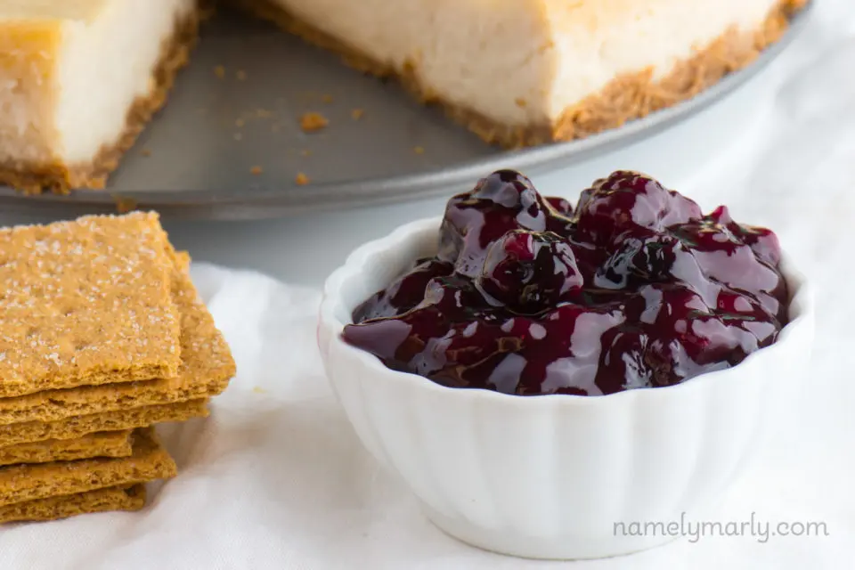 Blueberry sauce sits in front of a vegan cheesecake.