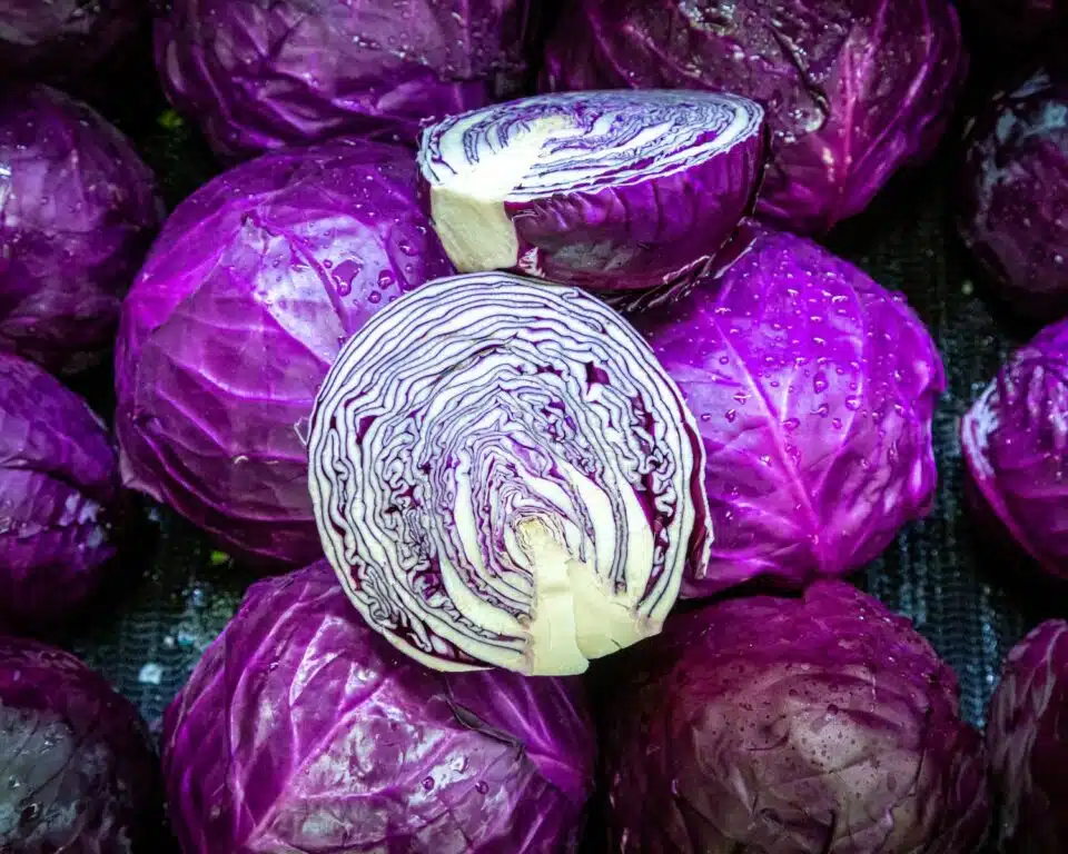 Looking down on several red cabbage, one of which has been cut in half, showing off the layers inside.