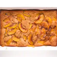 Looking down on a cobbler in a baking dish. There are slices of peaches that have risen to the top of the baked dish.
